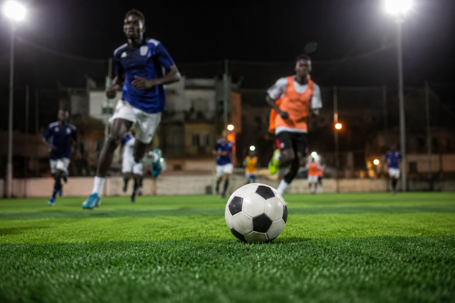 Match de football nocturne sur un terrain à Dakar